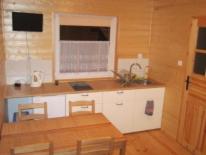 a kitchen with a table and a desk and a window at Domki Letniskowe Oaza Wicie in Wicie