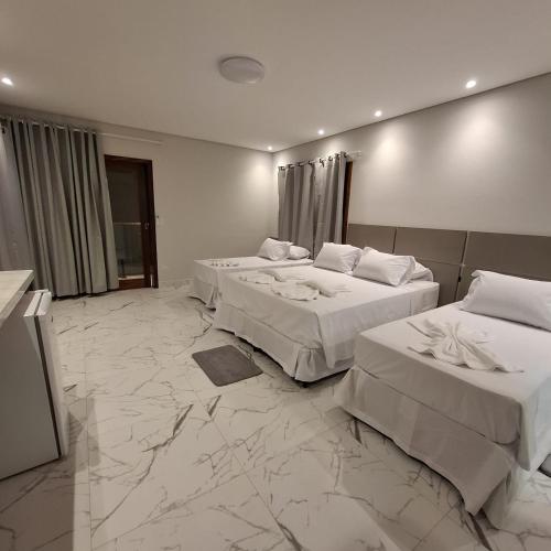 ein Hotelzimmer mit zwei Betten mit weißer Bettwäsche in der Unterkunft Reale Paraty in Paraty