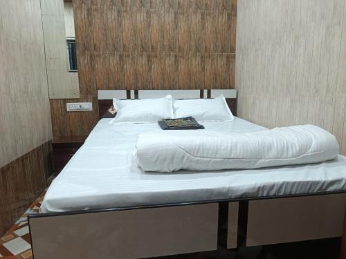 a bed with white sheets and a book on it at Hotel Bhagirath in Mumbai