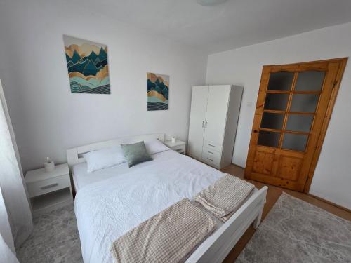 - une chambre avec un lit blanc et une porte en bois dans l'établissement Apartament Abby, à Sighişoara