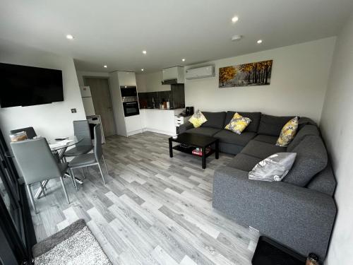 a living room with a couch and a table at Whispering Waves Guest house, Brighton-8 mins, Guests 4, Beachfront, Free parking, WiFi, Kitchen and AC in Peacehaven