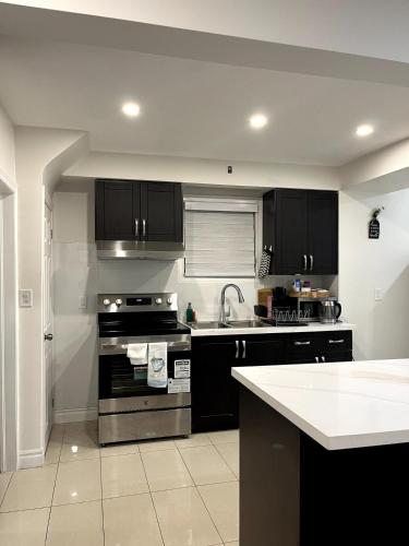 a kitchen with black cabinets and a stove top oven at Cozy 2-Bed with Kitchen and Patio in Midtown Toronto in Toronto