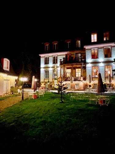 a large white house with tables and chairs at night at Hôtel Le Manoir in Barr