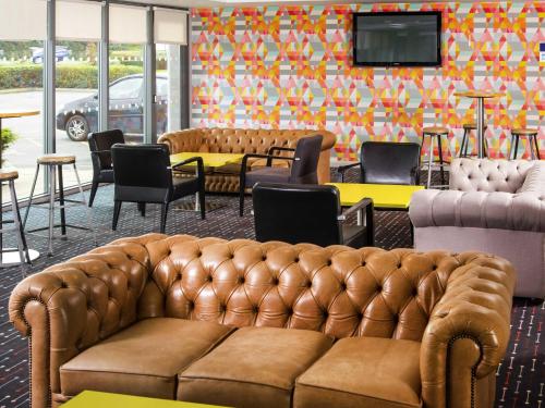 a living room with a couch and tables and chairs at ibis Styles Barnsley in Barnsley