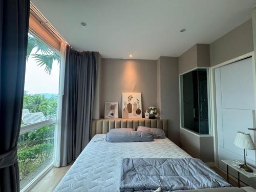 une chambre avec un lit et une grande fenêtre dans l'établissement Beachfront Luxury Studio Condo near Marriot Naiyang 50 1, à Phuket