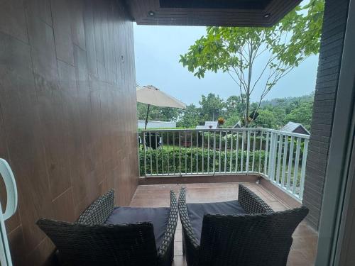 - un balcon avec 2 chaises et un parasol dans l'établissement Beachfront Luxury Studio Condo near Marriot Naiyang 50 1, à Phuket