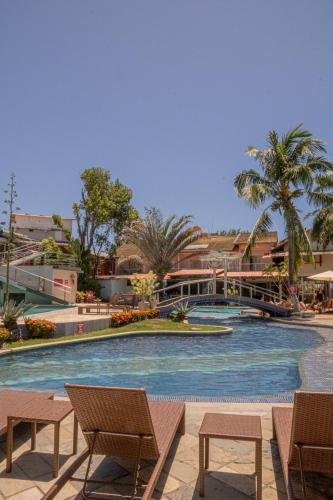 a large swimming pool with chairs and palm trees at Ramada by Wyndham Porto Seguro Praia in Porto Seguro