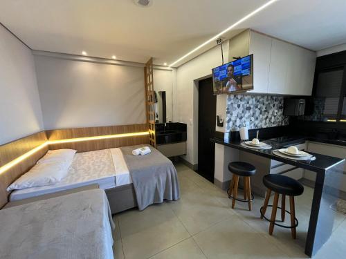 a bedroom with a bed and a desk and a kitchen at Haven Residence in Uberlândia