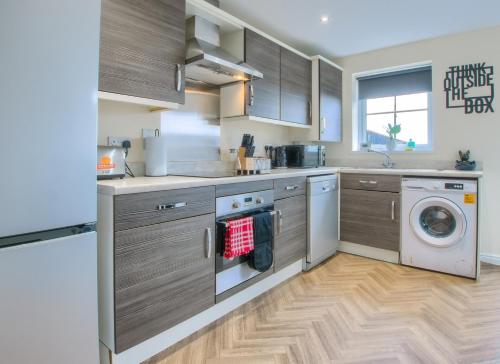 a kitchen with wooden cabinets and a washer and dryer at Sunderland Haven: Modern 4-Bedroom Family Retreat in Sunderland