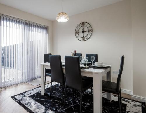 a dining room table with chairs and a clock on the wall at Sunderland Haven: Modern 4-Bedroom Family Retreat in Sunderland