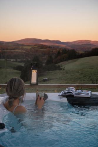 a girl in a jacuzzi tub with a camera at The Byre, Summerhill Farm Stays in Balmaclellan