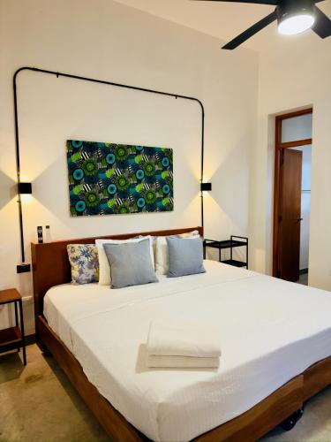 a bedroom with a large bed with a painting on the wall at Casa Lluavi - Caliope in Mérida