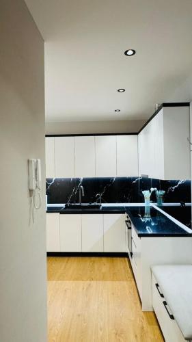a kitchen with white cabinets and black counter tops at Gloria New Bazaar Apartment in Tirana