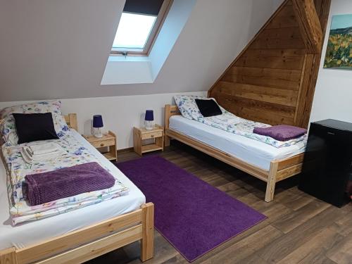two beds in a room with a purple rug at Agroturystyka nad potokiem in Domaszków