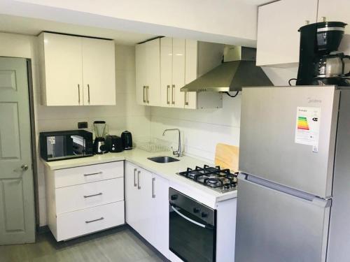 eine Küche mit weißen Schränken und einem weißen Kühlschrank in der Unterkunft Mahiahouse in Santiago