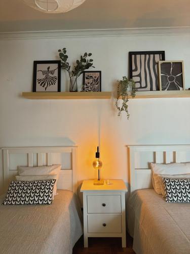 a bedroom with two beds and a night stand with a lamp at Cantinho da Avó Mifá in Lisbon