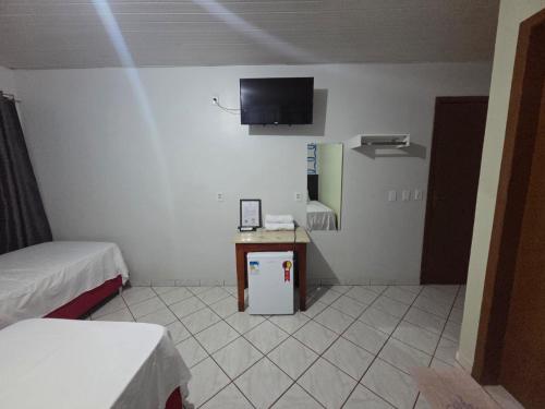 een kamer met een kleine koelkast en een tv aan de muur bij Hotel Danubio in Cuiabá