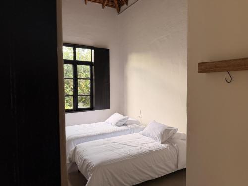 two beds in a white room with a window at Casamía in Medellín