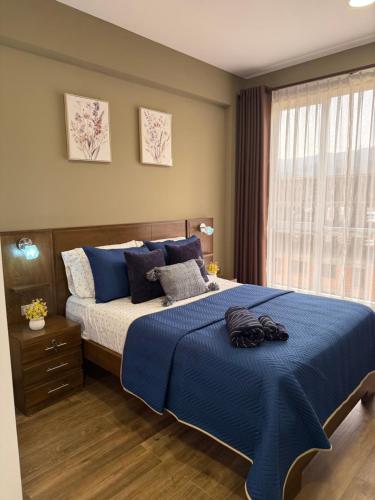 a bedroom with a bed with blue sheets and a window at El departamento de Verito in Cochabamba