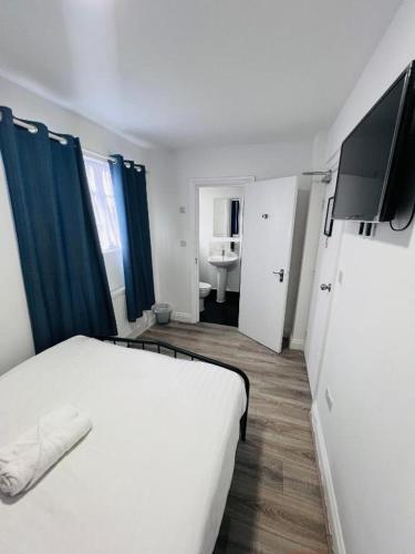 Un dormitorio con una cama blanca y un televisor. en TBH Hotel, en Barking