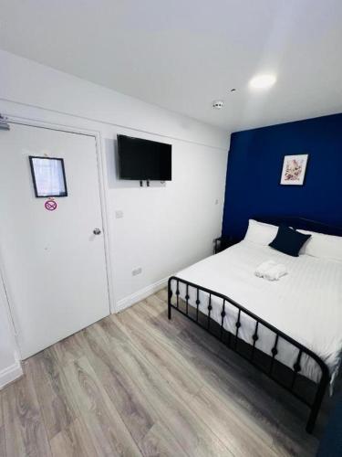 Un dormitorio con una cama con una pared azul. en TBH Hotel, en Barking