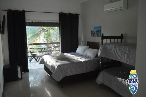 a bedroom with two beds and a balcony with a table at Tony Pousada Hotel Geribá in Búzios
