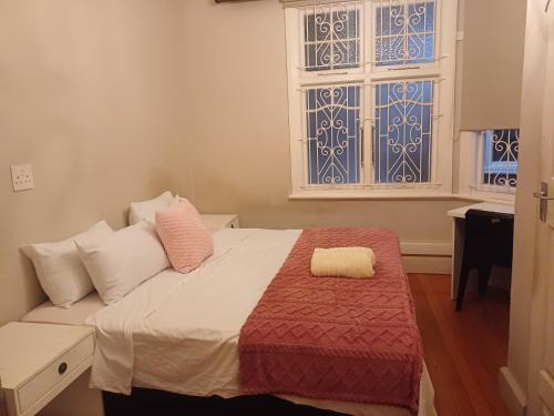 a bedroom with a bed with a red blanket and two windows at Nsimbini 430 Lena Ahrens in Durban