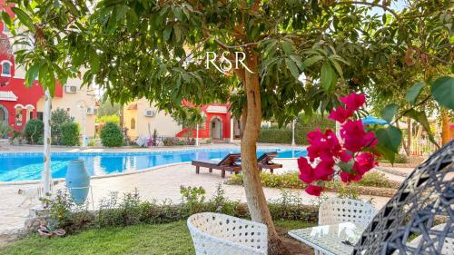 a table and chairs under a tree next to a pool at Green Garden Resort in Hurghada