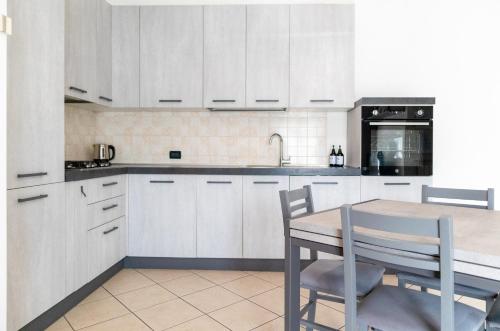 uma cozinha com armários brancos e uma mesa e cadeiras em Mira Venice Apartment em Mira