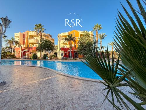 a swimming pool in a resort with palm trees and buildings at Green Garden Resort in Hurghada