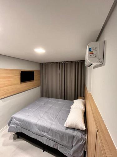 a small bedroom with a bed and a tv at Priority Praia grande in Praia Grande