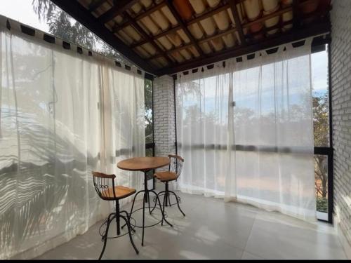 uma sala com uma mesa e duas cadeiras e janelas grandes em Pousada Vila Margarida em Chapada dos Guimarães