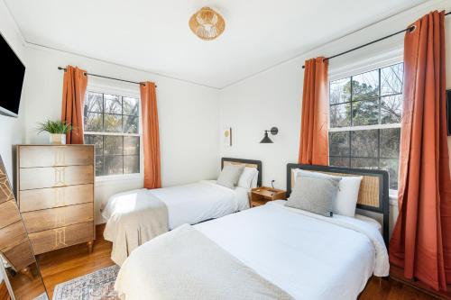 twee bedden in een slaapkamer met oranje gordijnen bij Sage & Stone Cottage in Lynchburg
