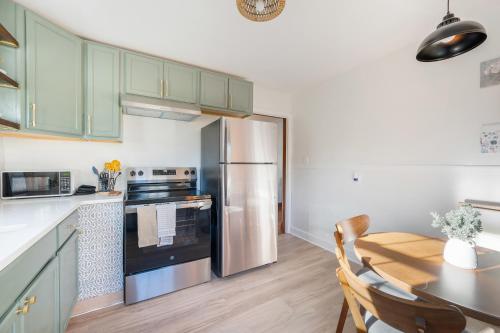 een keuken met groene kasten, een tafel en een koelkast bij Sage & Stone Cottage in Lynchburg