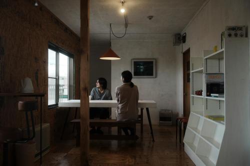 two people sitting at a table in a kitchen at Kamifu INN in Kami-furano