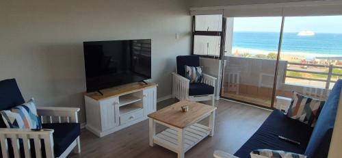 a living room with a television and a view of the ocean at 59 De Valle, Diaz Beach in Mossel Bay