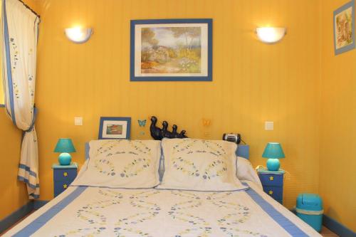 a bedroom with a bed with yellow walls and two lamps at La Roche Bleue in Saint-Bois