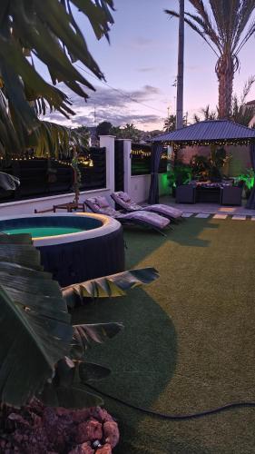 a backyard with a hot tub and palm trees at Villa romántica en Murcia con jacuzzi privado in Los López