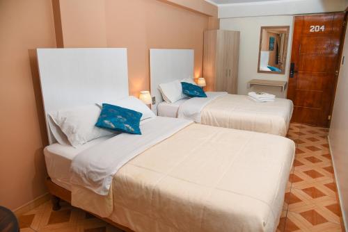 a hotel room with two beds with blue pillows at Hotel Los Inkas in Huaraz