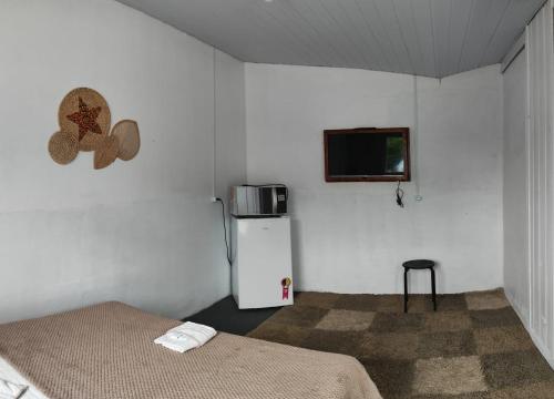 a room with two beds and a refrigerator and a tv at Suítes Simples Casa Madeira - Blumenau in Blumenau