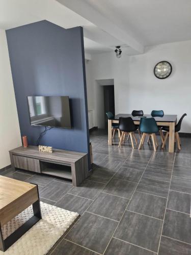 a living room with a tv and a table and chairs at Au Clerc de Lune in Broye