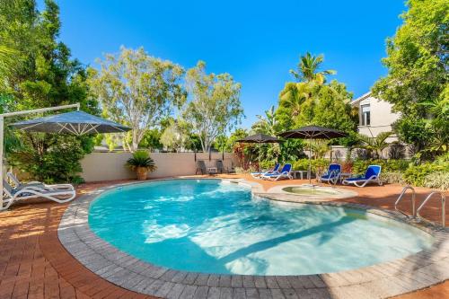 a large swimming pool with chairs and umbrellas at At The Sound Noosa in Noosaville