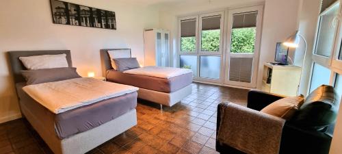 a room with two beds and a chair and windows at Ferienwohnung Pulvermühlenteich in Seevetal