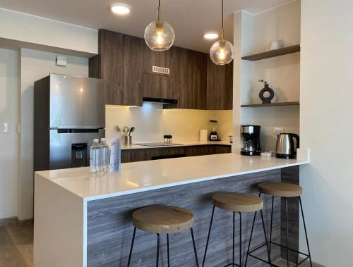 a kitchen with a counter with two stools and a refrigerator at Modern 2BR with Balcony in San Isidro in Lima