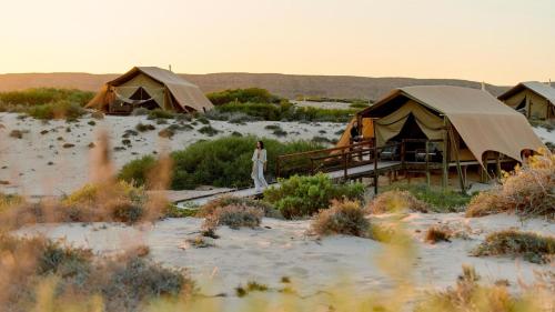 a woman standing in front of tents in the desert at Sal Salis Ningaloo Reef in Exmouth