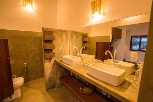 a bathroom with two sinks and a toilet at Casa Galo Pretto in Galinhos