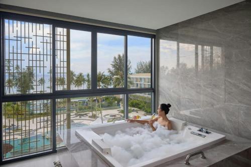 una donna seduta in bagno in una vasca da bagno di Four Points by Sheraton Bintan, Lagoi Bay a Lagoi
