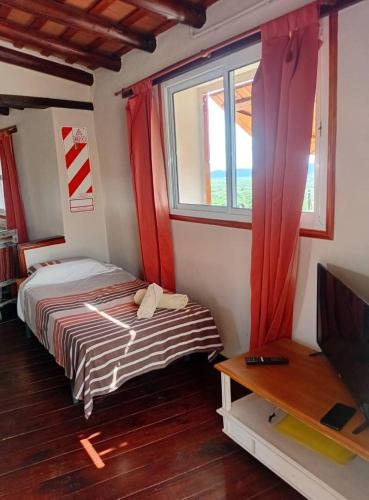 a bedroom with a bed with red curtains and a television at Suite's on the rock's in Nono