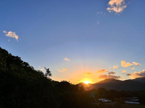 a sunset with the sun setting over the mountains at NOVIDADE! Apartamento Bella Vita Bertioga in Bertioga