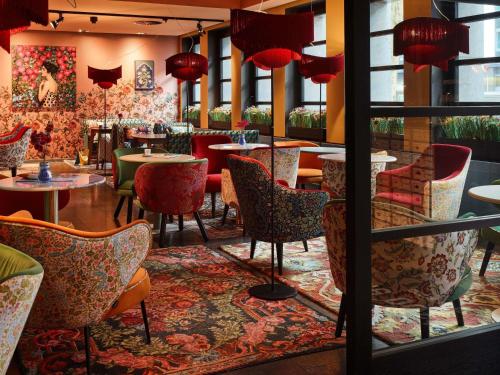 a restaurant with tables and chairs and red lamps at 25hours Hotel The Goldman in Frankfurt